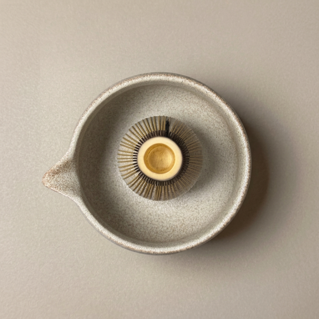Top view of a purple bamboo matcha whisk inside a speckled ceramic bowl.